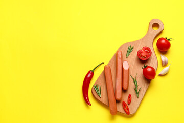 Board of tasty sausages with chilli and tomatoes on yellow background