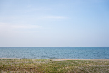 Obraz premium Endless sea view with a clean beach and some grass.
