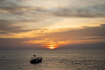 Fishing boat on the sea with sunset background.