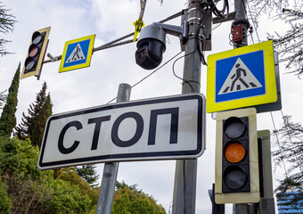 The sign "Stop" and a CCTV camera in front of a traffic light with a pedestrian crossing