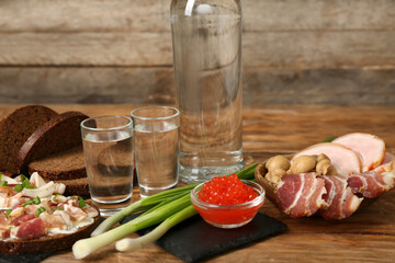Shots with cold vodka and snacks on wooden background