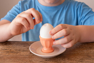 Egg in egg cup for kids breakfast. Egg in the hands of a child.
