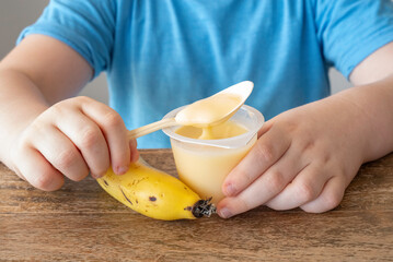 Banana yogurt in the hands of a child.