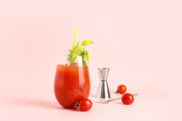 Glass of bloody mary with celery and tomatoes on pink background