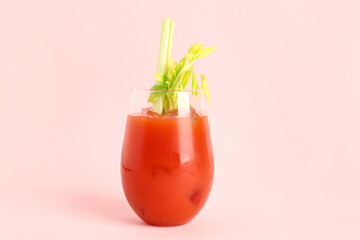 Glass of bloody mary with celery on pink background