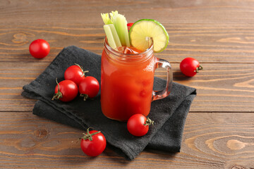 Mason jar of bloody mary with celery and lime on wooden table