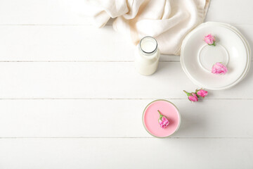 Glass panna cotta with beautiful pink rose flowers on white wooden table