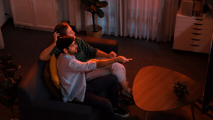 Top view of happy caucasian father and relaxed mother watching TV together while dad holding remote...
