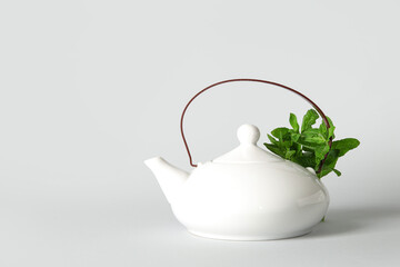 Teapot of fresh mint tea on grey background