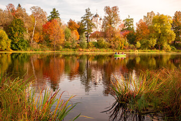 Fototapeta premium A picturesque view of the autumn landscape and pond, with boating with tourists. Bolshye Vyazemye, Odintsovo district, Moscow region