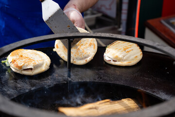 A person is actively and skillfully cooking food on a grill using a spatula as they prepare a delicious meal, showcasing their culinary skills and creativity in the kitchen