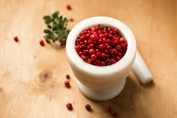 A white stone mortar full of ripe wild lingonberries
