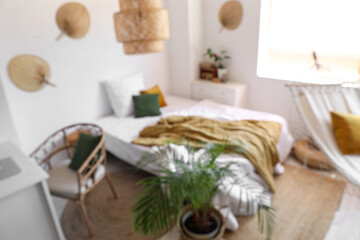 Blurred view of children's bedroom with cozy bed, hammock and houseplant