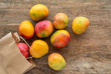 Mango in paper pack over wooden background. Top view.
