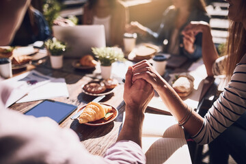 Holding hands, people and respect with prayer for food, finance planning and budget documents of teamwork. Staff, thanks and meeting with paperwork, graphs and profit stats for kpi accounting at cafe