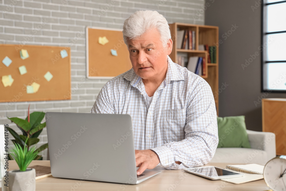 Sticker Confused senior man using laptop at home