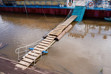 A sturdy wooden bridge constructed over a flooded river, designed to allow safe passage and...