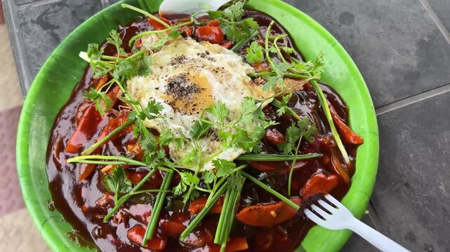 Cinematic shot of Chicken Schezwan Noodles or Hakka or Chow Mein with egg poach in green plate.