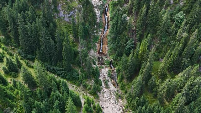 Slow aerial reveal of Cascada Cailor, surrounded by lush green vegetation in the Rodnei Mountains, Bucovina, Romania