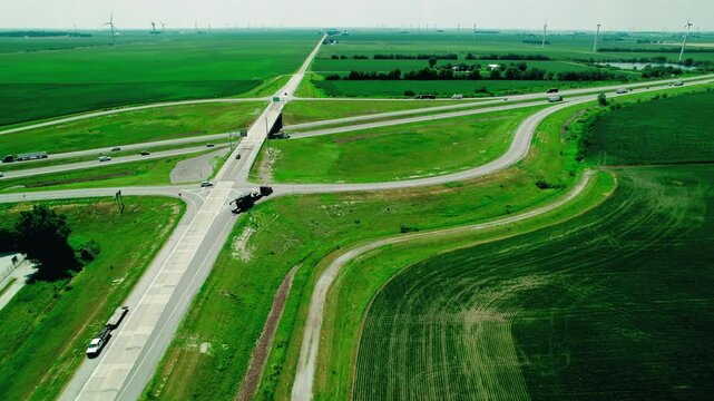 Following RGN trailer Semi truck with oversize load in Indiana, USA on countryside roads. Overview aerial - dynamic shot.