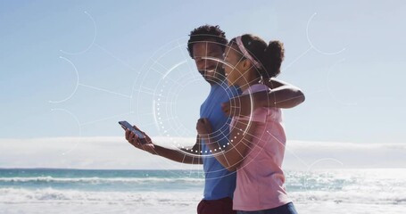 Couple on beach with smartphone, digital interface animation over them - Powered by Adobe