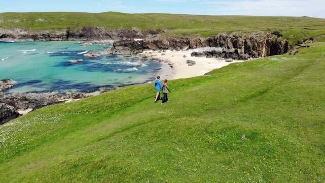 A couple goes for a walk in the Outer Hebrides. The water looks like the Caribbean.