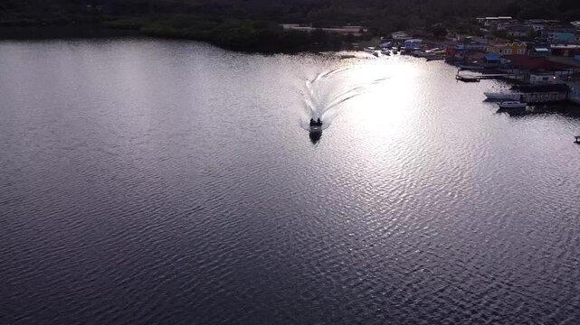 A boat cruising through the Caribbean waters, surrounded by lush vegetation and dramatic mountain peaks.