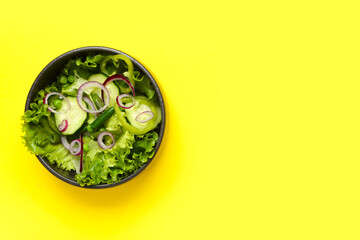 Bowl of tasty vegetable salad on yellow background