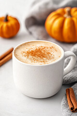 Minimalist pumpkin spice latte in a sleek white cup with a tiny pumpkin and cinnamon stick beside it empty background with soft autumn tones 