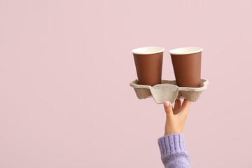 Female hand with brown takeaway paper cups and holder on purple background