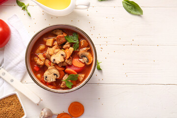 Bowl of tasty beef stew on white wooden background