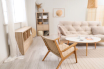 Blurred view of living room interior with white sofa, armchair and coffee table