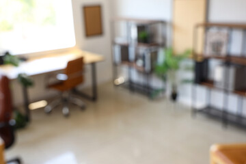 Blurred view of modern office with workplace and shelf units