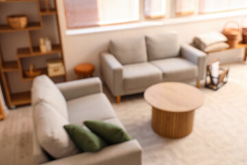 Blurred view of light living room with sofas and table