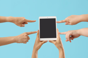 Women pointing at blank tablet computer on blue background