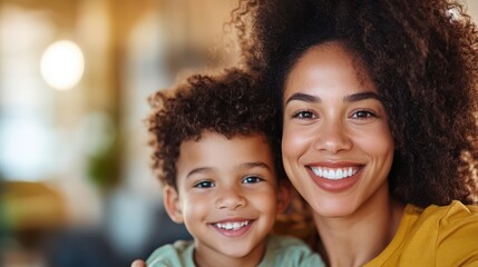 Fototapeta premium A mother with curly hair and her child smile brightly at the camera, showing apparent happiness and a strong bond, set in a warm environment highlighting familial joy.