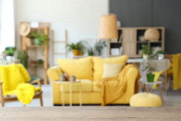 Blurred view of modern living room with yellow sofa and houseplants
