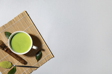 Composition with cup of fresh matcha tea, powder and chasen on grey background