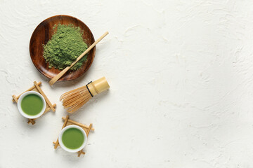 Composition with cups of fresh matcha tea, powder and accessories on light background