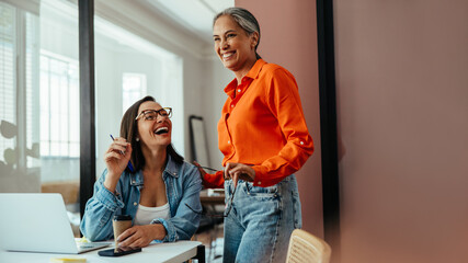 Happy employees laughing and collaborating in a modern office