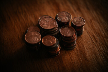 Stacks of coins on a wooden table. Shallow depth of field.