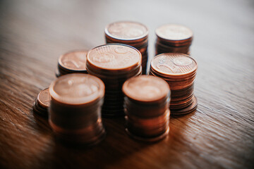 Stacks of coins on a wooden table. Shallow depth of field.