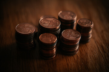 Stacks of coins on a wooden table. Shallow depth of field.