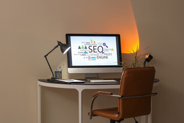 Workplace with modern computer and glowing lamp in stylish office at evening. SEO concept