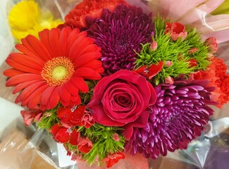 A mixed of red daisy, red roses and purple chrysanthemums as bouquet of flowers