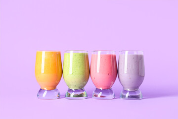 Glasses of different fresh smoothie on lilac background