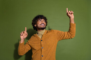 Photo portrait of handsome young guy dance point look up empty space dressed stylish brown garment isolated on khaki color background