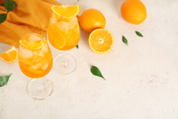 Glasses of Aperol spritz cocktail with oranges and leaves on white background