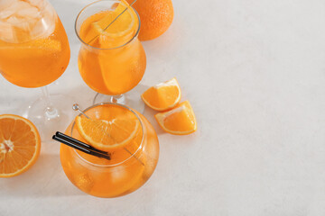 Glasses of Aperol spritz cocktail with oranges on white background