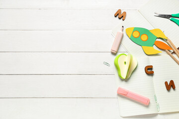 Paper rocket with notebook and different stationery on white wooden background. Top view